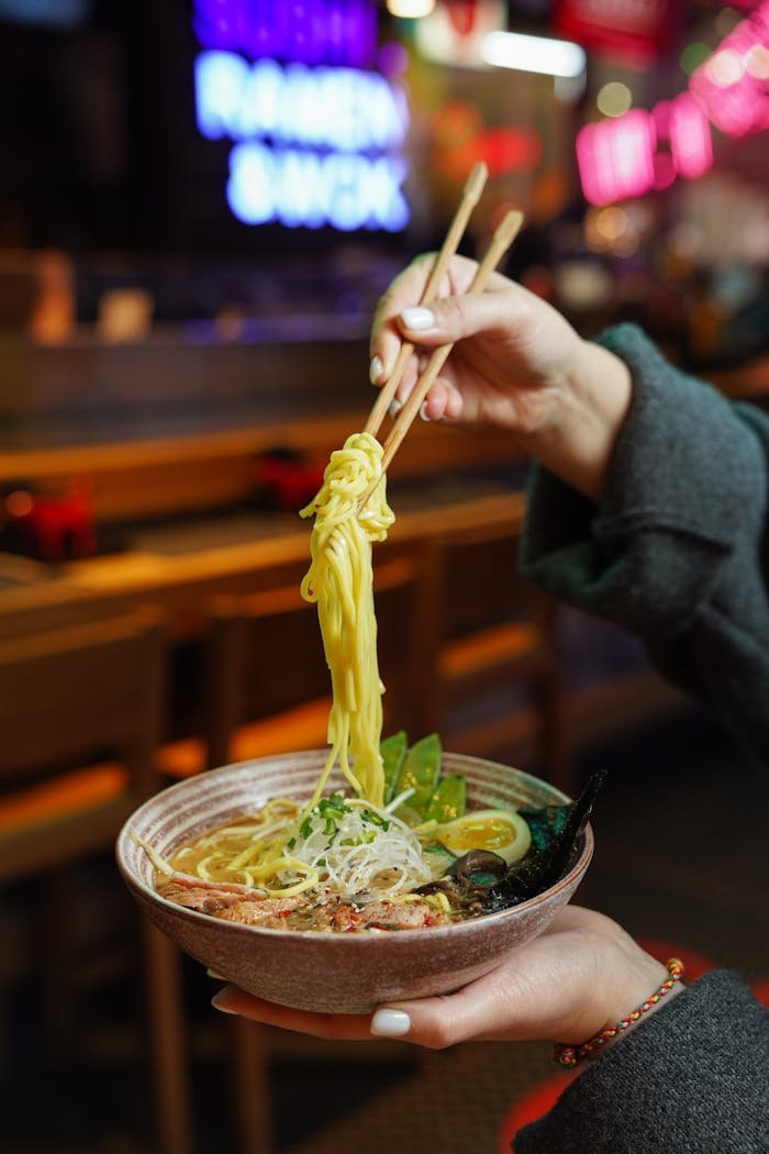 Tantalizing close-up of ramen noodles being lifted by chopsticks, emphasizing the vibrant ingredients and textures.