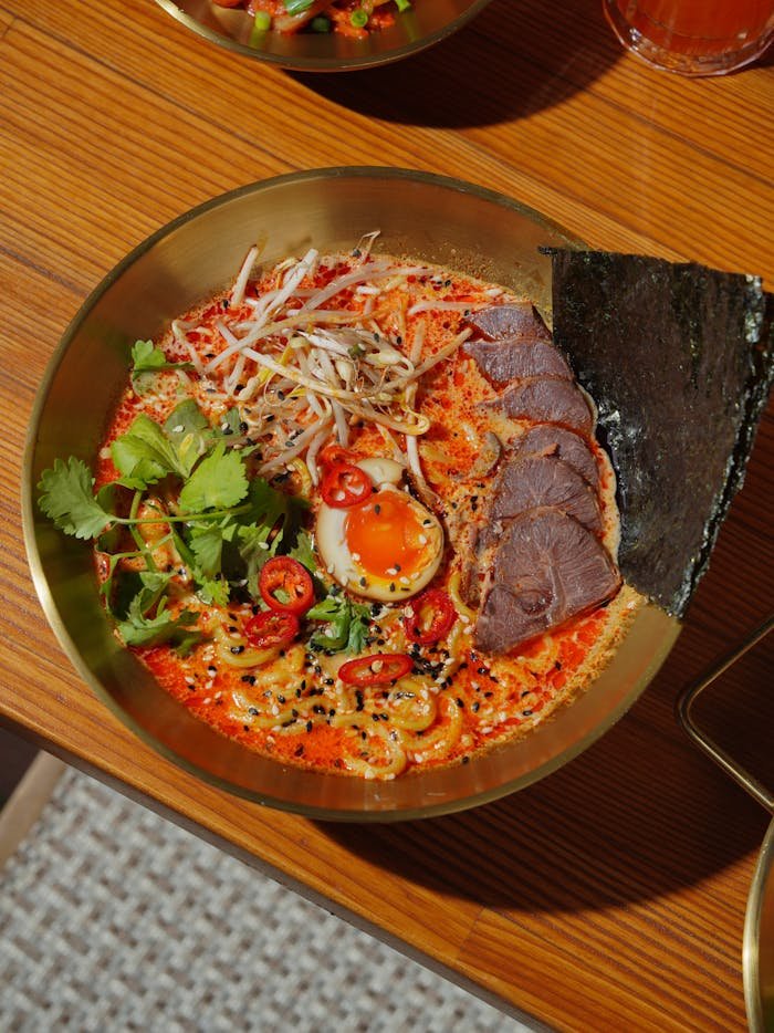 A vibrant bowl of spicy ramen with pork, egg, and fresh toppings.